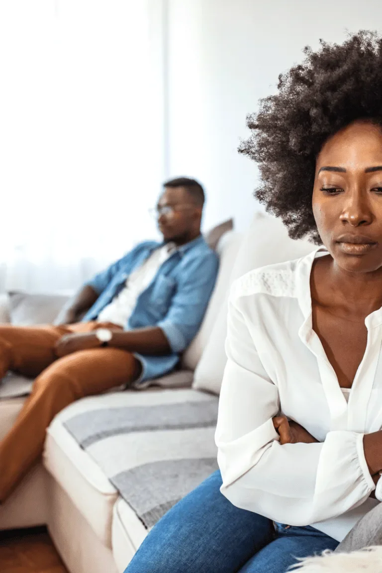A couple sitting at a distance from each other on a couch, how to help your wife heal